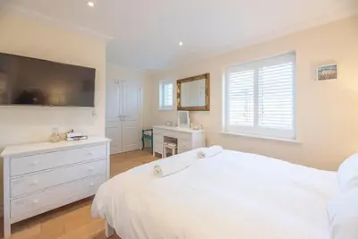 a white bedroom with a large bed and a desk at Fromus Rise, Saxmundham in Saxmundham