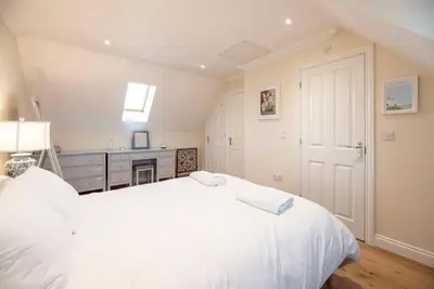 a white bedroom with a large white bed and a desk at Fromus Rise, Saxmundham in Saxmundham