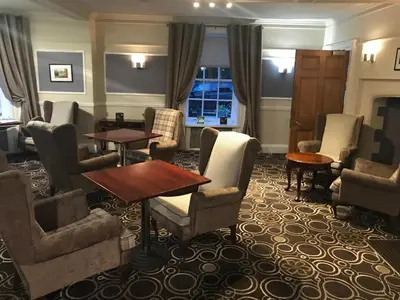 a waiting room with chairs and tables and a fireplace at Best Western Priory Hotel in Bury Saint Edmunds