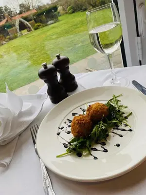 a plate of food and a glass of wine on a table at Best Western Priory Hotel in Bury Saint Edmunds