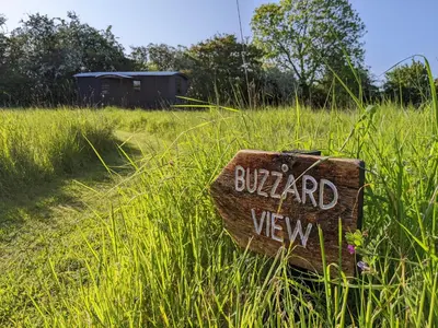 a sign sitting in the grass in a field at Blue Sky Huts in Chediston