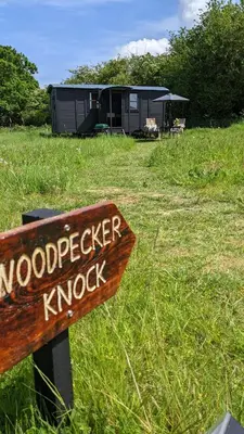 a wooden sign in a field with a building at Blue Sky Huts in Chediston
