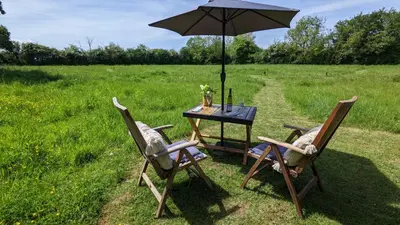 a table with two chairs and an umbrella in a field at Blue Sky Huts in Chediston