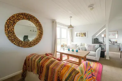 a living room with a couch and a mirror at Fishermans Loft - A seaside house in Thorpeness with direct access to the beach - Aldeburgh Coastal Cottages in Thorpeness