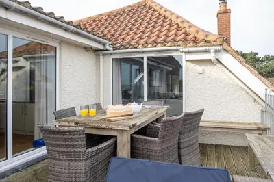 a table with chairs and a cake on a patio at Fishermans Loft - A seaside house in Thorpeness with direct access to the beach - Aldeburgh Coastal Cottages in Thorpeness