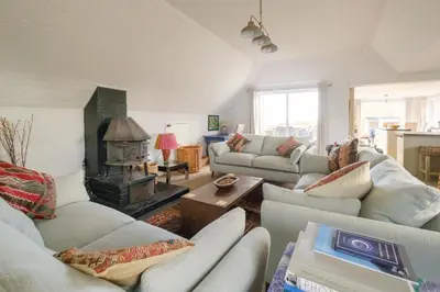 a living room with couches and a fire place at Fishermans Loft - A seaside house in Thorpeness with direct access to the beach - Aldeburgh Coastal Cottages in Thorpeness