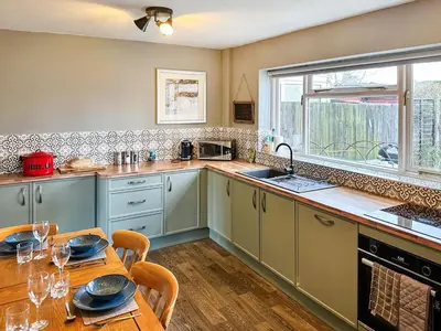 a kitchen with a table and a window and a sink at Heath View in Saxmundham