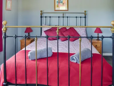 a bed with a red blanket and two towels at Heath View in Saxmundham