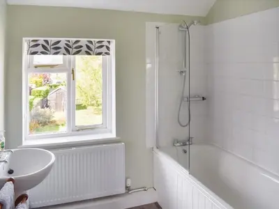 a bathroom with a sink and a tub and a window at Heath View in Saxmundham