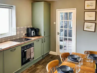 a kitchen with green cabinets and a table with chairs at Heath View in Saxmundham