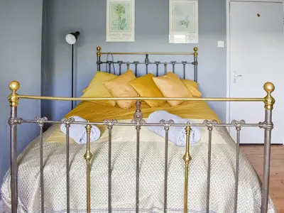 a metal bed with yellow pillows in a bedroom at Heath View in Saxmundham
