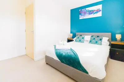 a bedroom with a large bed with a blue wall at Cambridge 4 Bedroom Sleeps 9 Wi-Fi Garden, LONG STAYS ACCEPTED- Orchid House in Cambridge