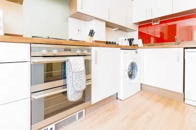 a kitchen with white cabinets and a washer and dryer at Cambridge 4 Bedroom Sleeps 9 Wi-Fi Garden, LONG STAYS ACCEPTED- Orchid House in Cambridge