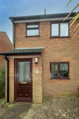 a brick house with a brown door and windows at 52 Carr Avenue in Leiston