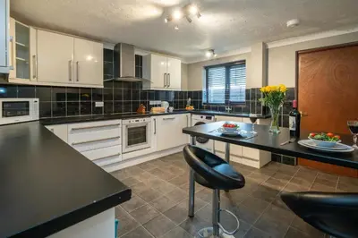 a kitchen with white cabinets and a black counter top at 52 Carr Avenue in Leiston