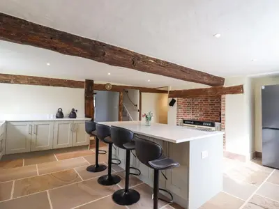 a kitchen with white countertops and black bar stools at West House Farm in Leiston