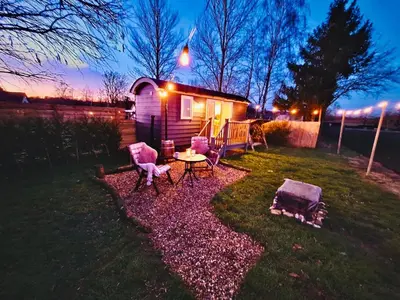a small house with a table and chairs in the yard at Whiskers and Woods Shepherd Hut in Denham