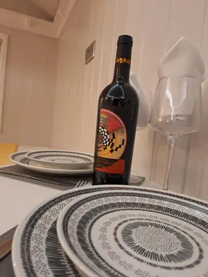 a bottle of wine sitting on a table with plates at Whiskers and Woods Shepherd Hut in Denham