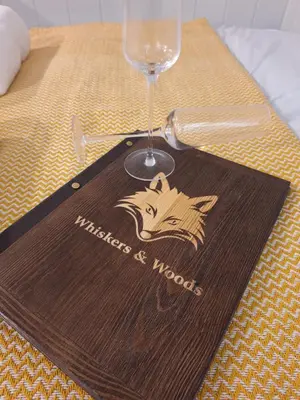 a wooden napkin with a wine glass on a table at Whiskers and Woods Shepherd Hut in Denham
