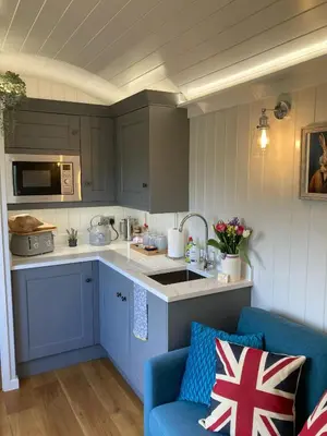 a kitchen with blue cabinets and a blue couch at Whiskers and Woods Shepherd Hut in Denham
