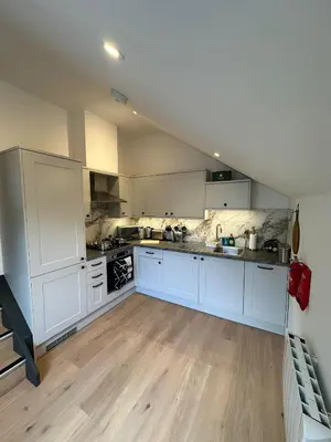 a large kitchen with white cabinets and wooden floors at Central Cambridge Apartments by Tas in Cambridge