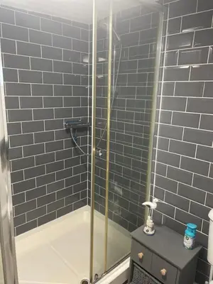 a bathroom with a shower with blue tiles at Judith Barge in Colchester