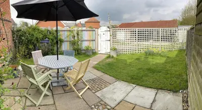 a patio with a table and chairs and an umbrella at Love Heart Cottage in Wickham Market