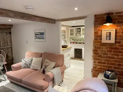 a living room with a couch and a kitchen at Love Heart Cottage in Wickham Market