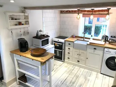 a kitchen with white appliances and a wooden floor at Love Heart Cottage in Wickham Market