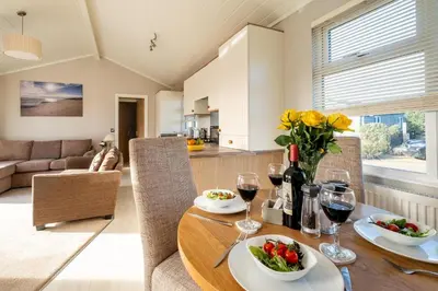 a dining room and living room with a table with wine glasses at Sea La Vie in Sizewell