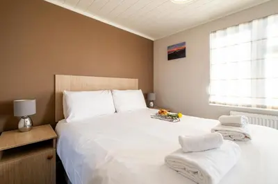a bedroom with a large white bed with towels on it at Sea La Vie in Sizewell