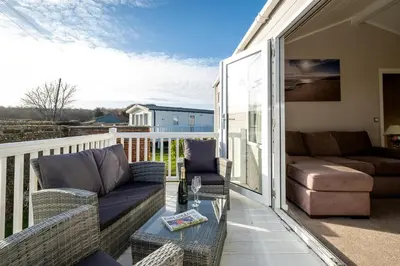 a patio with a couch and a table on a balcony at Sea La Vie in Sizewell