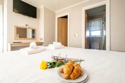 a plate of croissants and flowers on a bed at Sea La Vie in Sizewell
