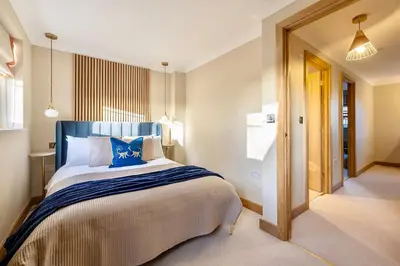 a bedroom with a large bed with a blue headboard at Luxury Stay, City Walk, Pool Table & Air Hockey, Garden, Parking, Business & Families - Oakview in Colchester