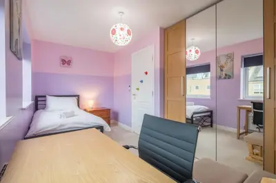 a bedroom with a bed and a table and a chair at Modern and Comfy 3 bed Cambridge House in Cambridge