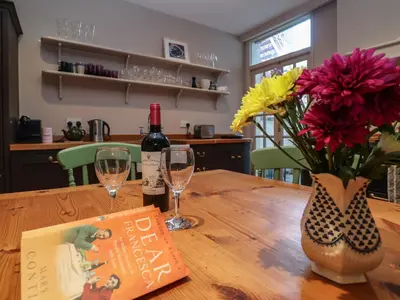 a bottle of wine and a vase of flowers on a wooden table at 11a Market Cross Place in Aldeburgh