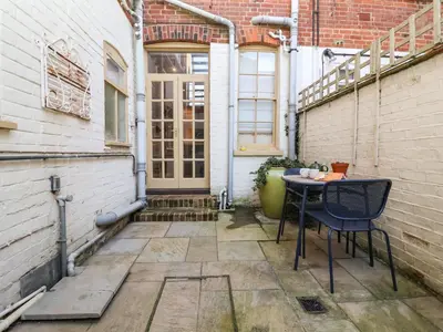 a patio with a table and chairs in front of a building at 11a Market Cross Place in Aldeburgh