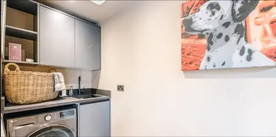 a kitchen with a washing machine and a painting on the wall at The Lodge, Saxmundham in Saxmundham