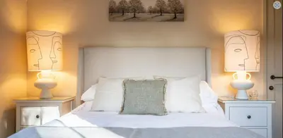 a bedroom with a white bed with two lamps at The Lodge, Saxmundham in Saxmundham