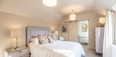 a bedroom with a large white bed with pillows at The Lodge, Saxmundham in Saxmundham