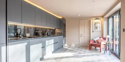 a kitchen with gray cabinets and a red chair at The Lodge, Saxmundham in Saxmundham