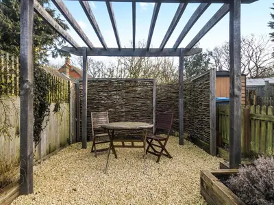 a table and chairs under a pergola in a garden at September Cottage in Wenhaston