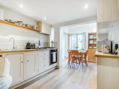 a kitchen with white cabinets and a table and chairs at September Cottage in Wenhaston