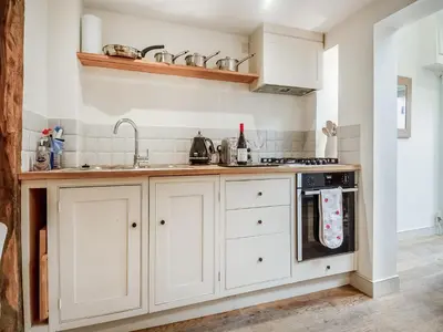 a kitchen with white cabinets and a sink at September Cottage in Wenhaston