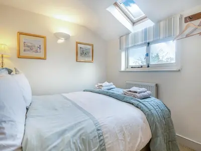 a bedroom with a bed and two windows at September Cottage in Wenhaston