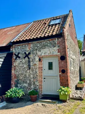 a small brick building with a white door at The Old Stable at Manor House, Middleton in Middleton