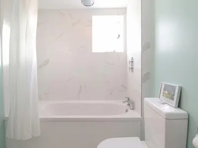 a white bathroom with a white tub and a toilet at Twosome in Halesworth