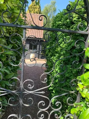 a gate to a garden with a bench and some bushes at Barn studio in Long Melford in Long Melford
