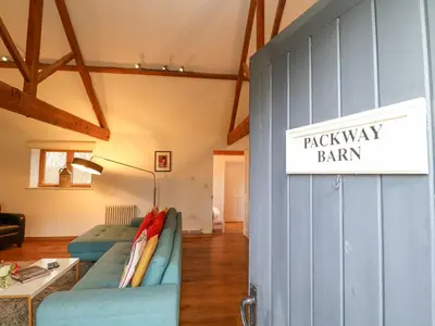 a room with a blue couch and a sign that reads back way barn at Packway Barn in Halesworth