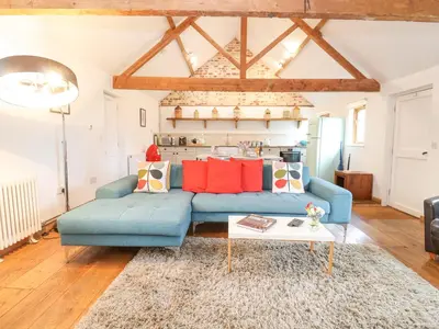 a living room with a blue couch and a table at Packway Barn in Halesworth
